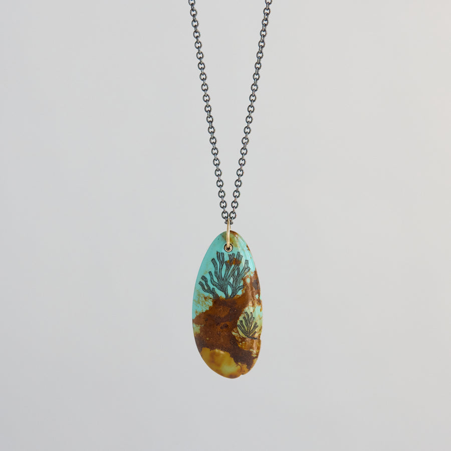 Necklace with a pendant featuring a seaweed design on a light gray background