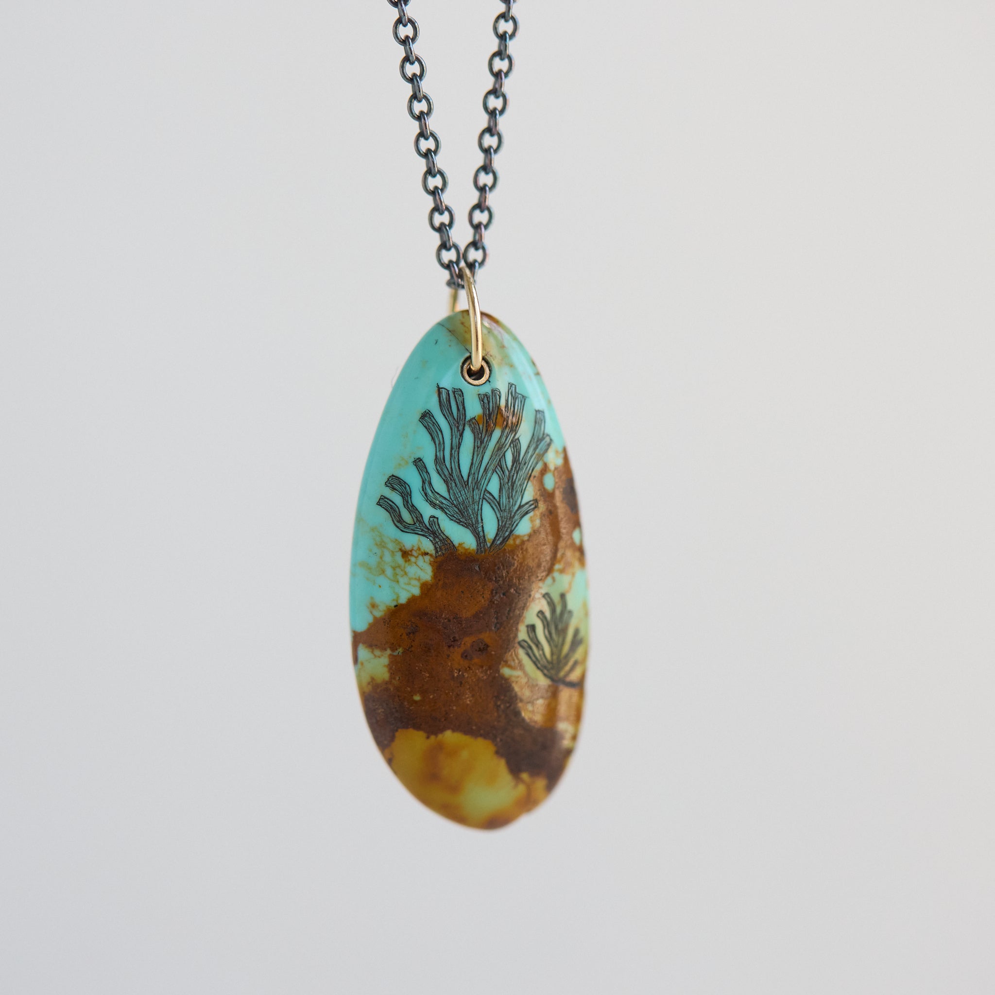 Necklace with a pendant featuring a design of seaweed on a light gray background