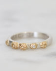 Silver ring with gold accents and a diamond on a light gray background