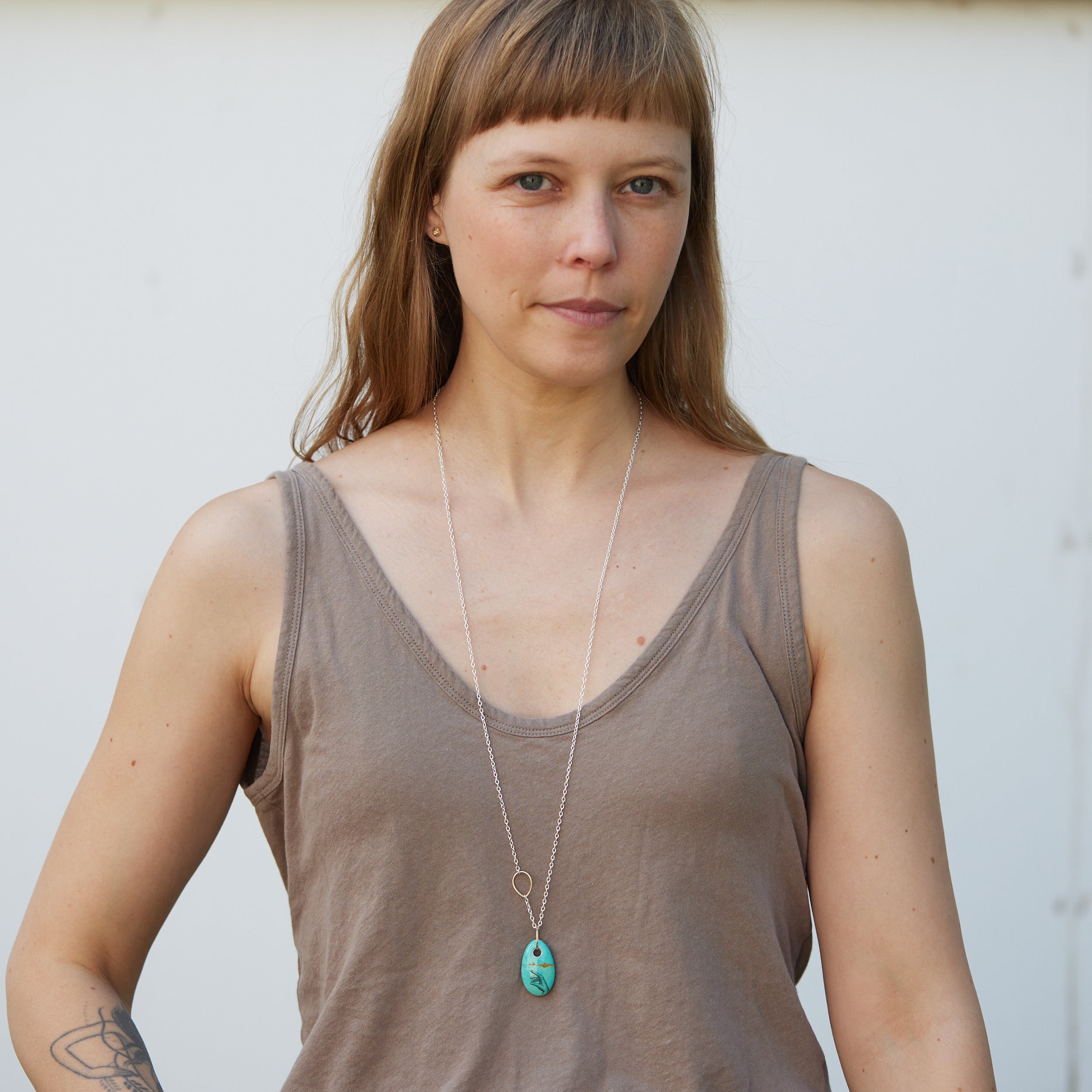 kingman turquoise bead with hand scrimshaw in ink. Pendant necklace with bright silver chain with gold egg link.