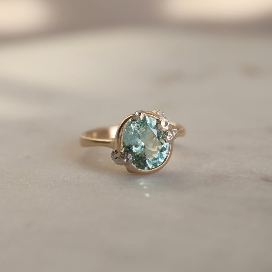 Gold ring with a green gemstone on a neutral background