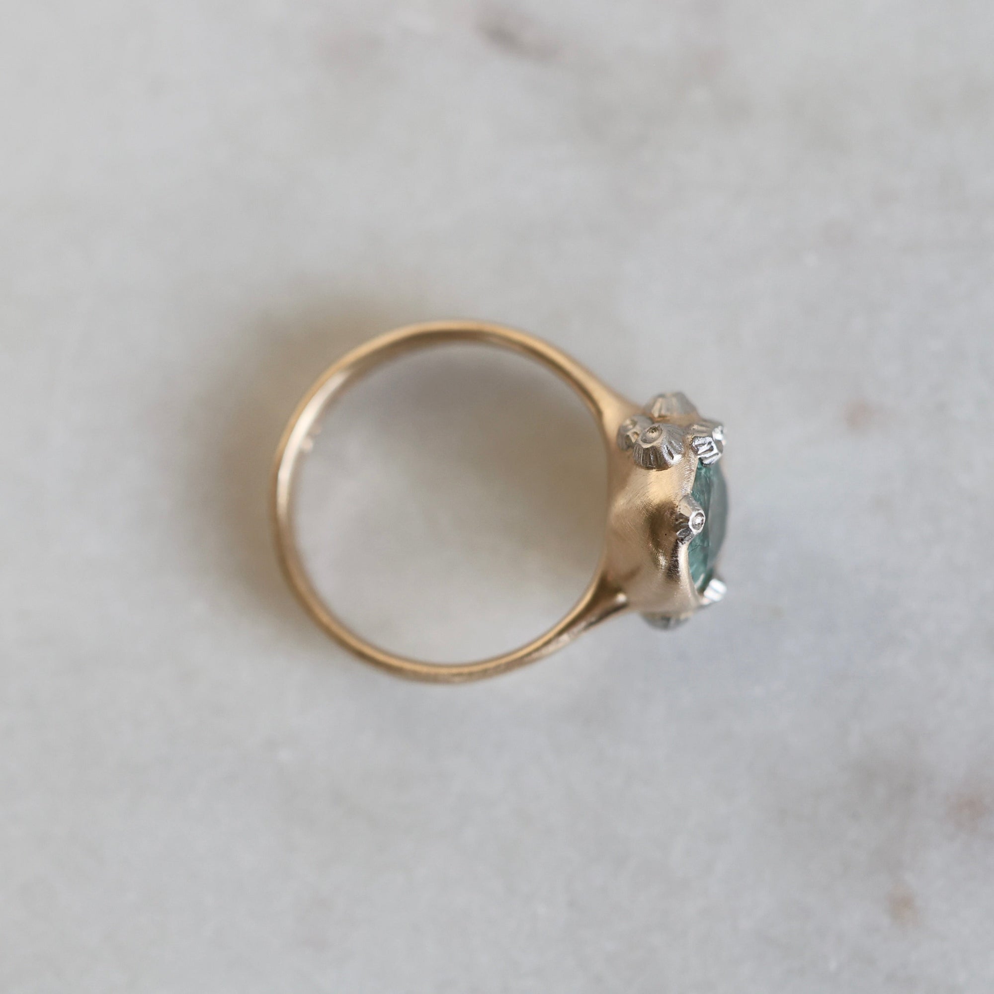 Gold ring with a gemstone on a light gray background