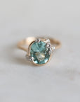 Gold ring with a green gemstone on a light gray background