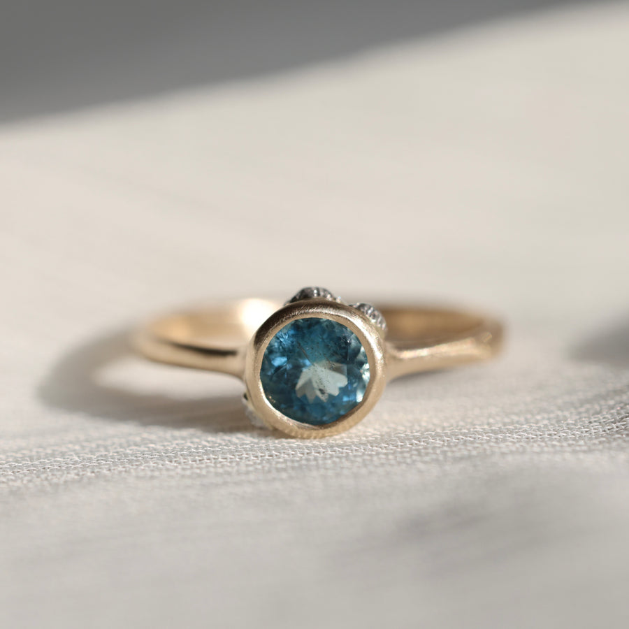 gold ring with blue stone on a pale fabric surface
