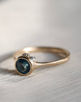 gold ring with blue stone on a pale fabric surface