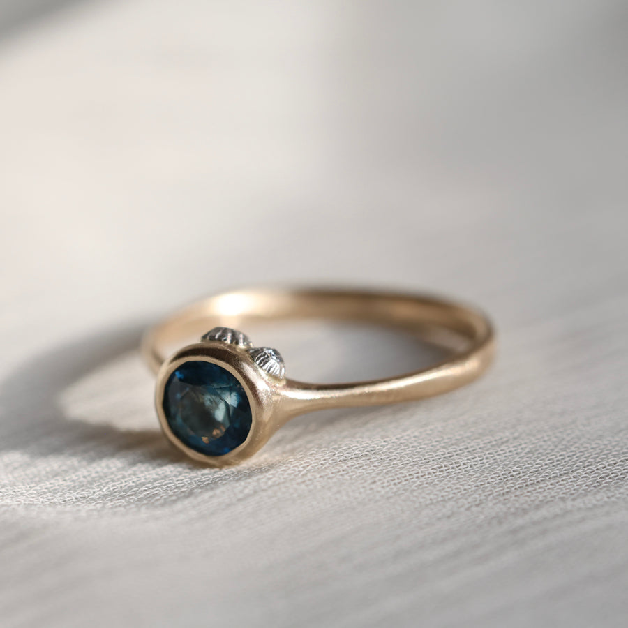 gold ring with blue stone on a pale fabric surface