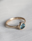 gold ring with blue stone on a pale fabric surface