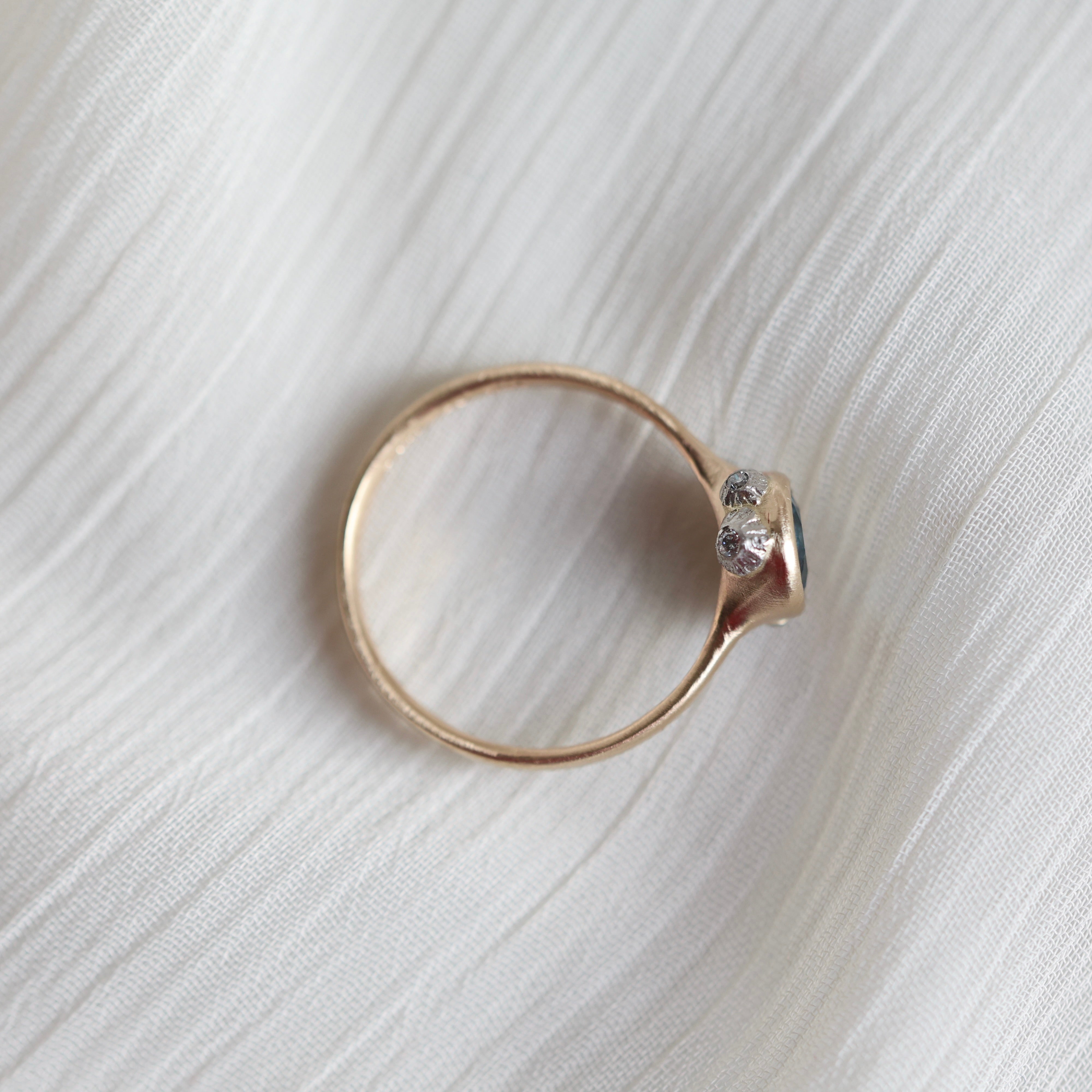 gold ring with blue stone on a pale fabric surface