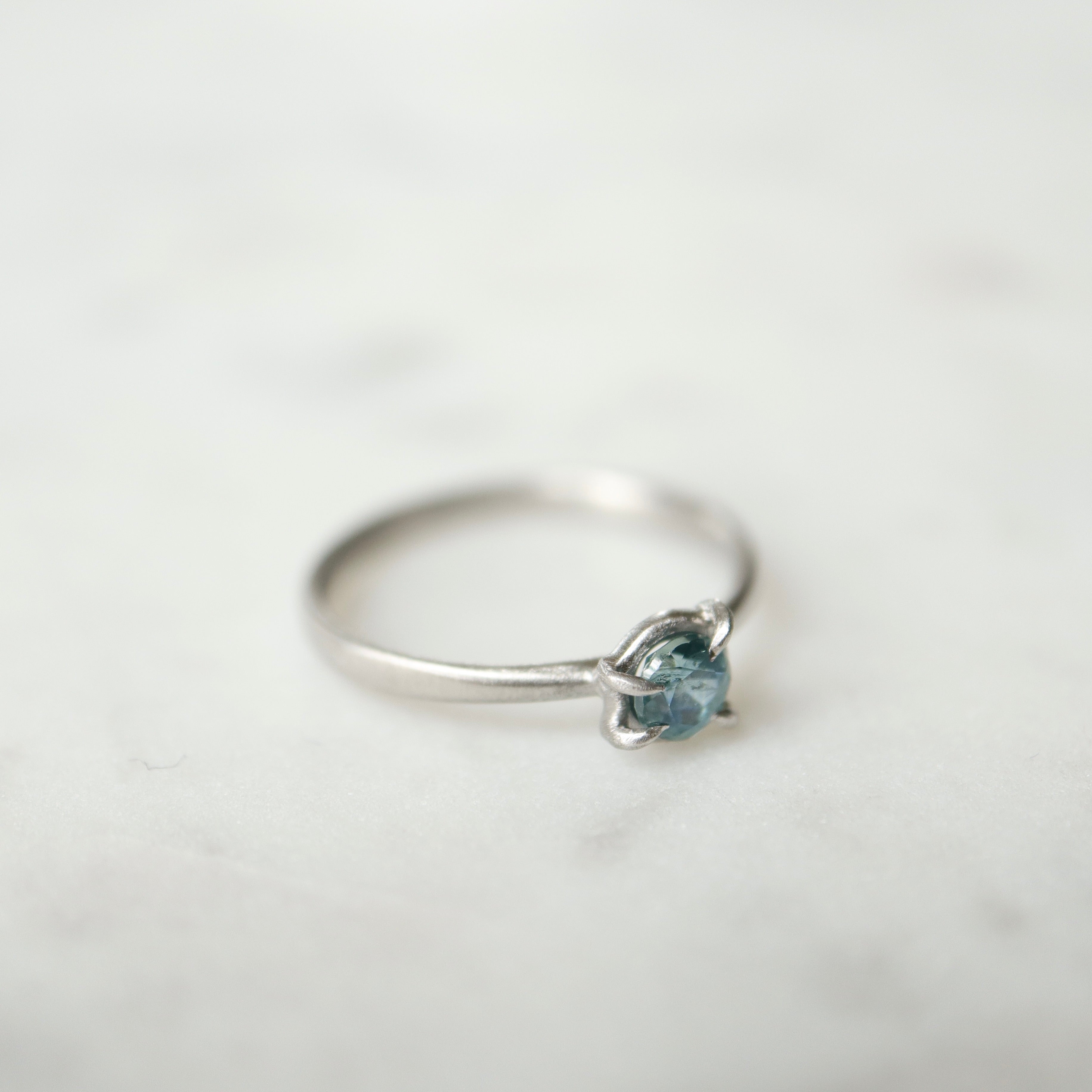 side view of blue montana sapphire stone set in a ring of platinum via prongs.