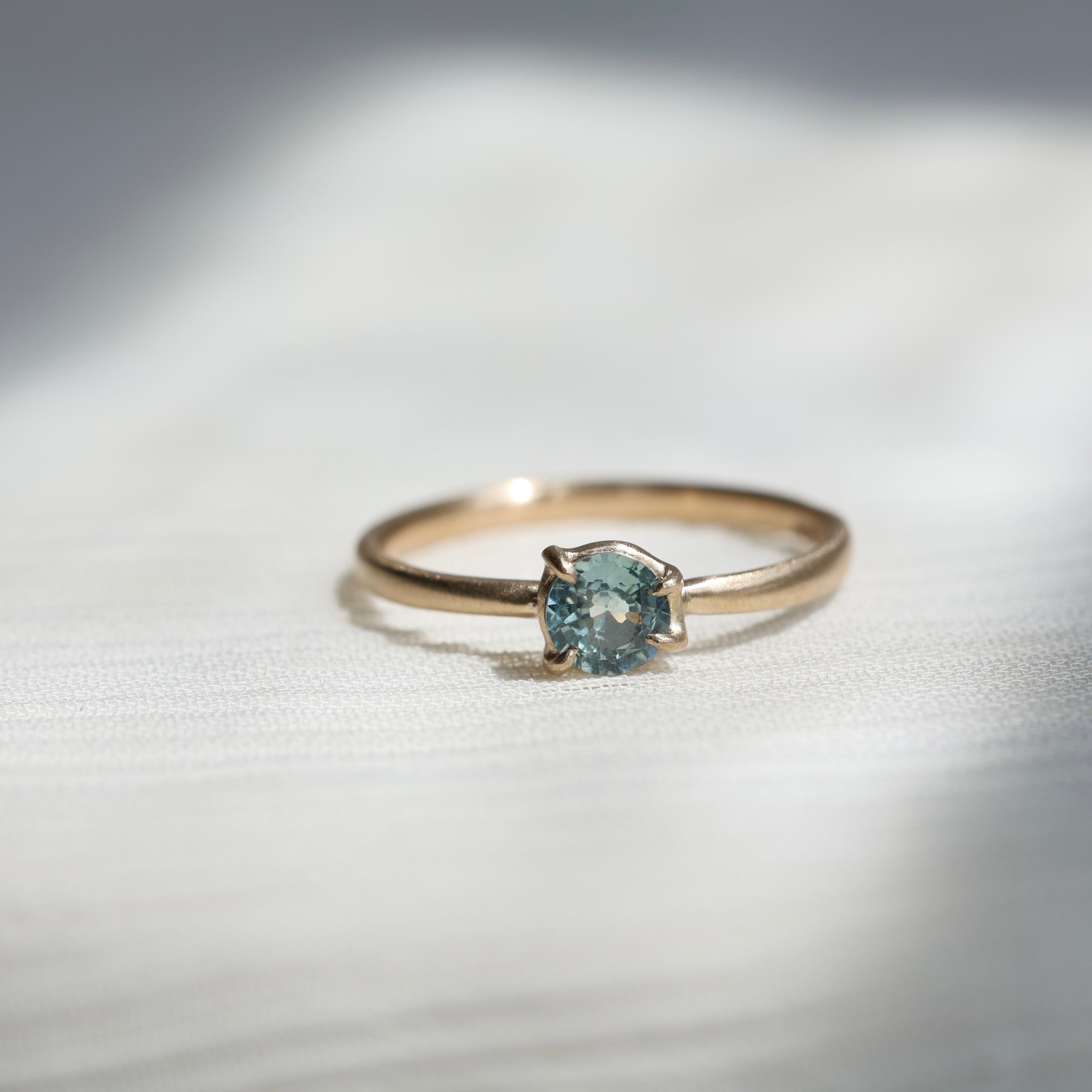 Gold ring with a light blue gemstone on a fabric background