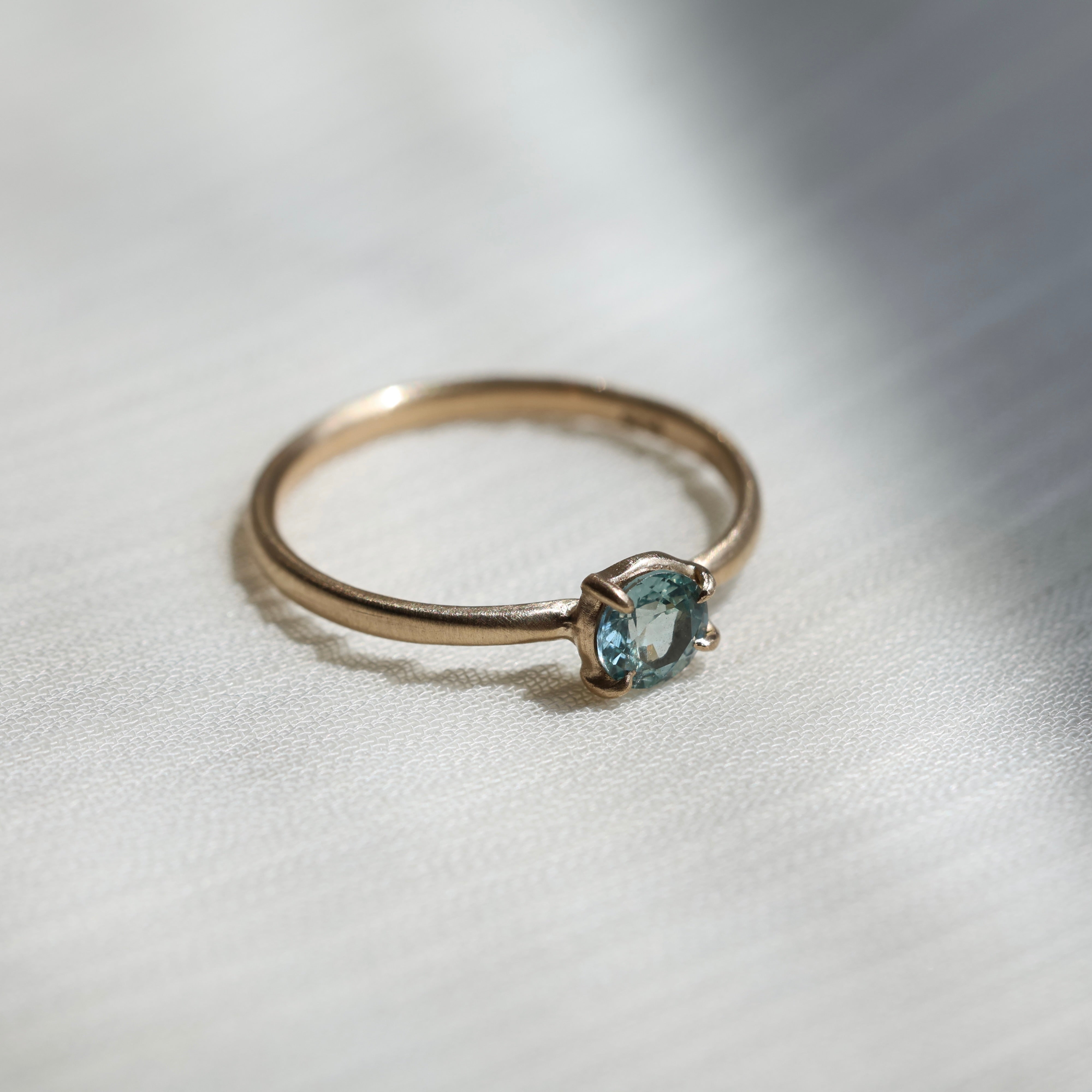 Gold ring with a light blue gemstone on a fabric background