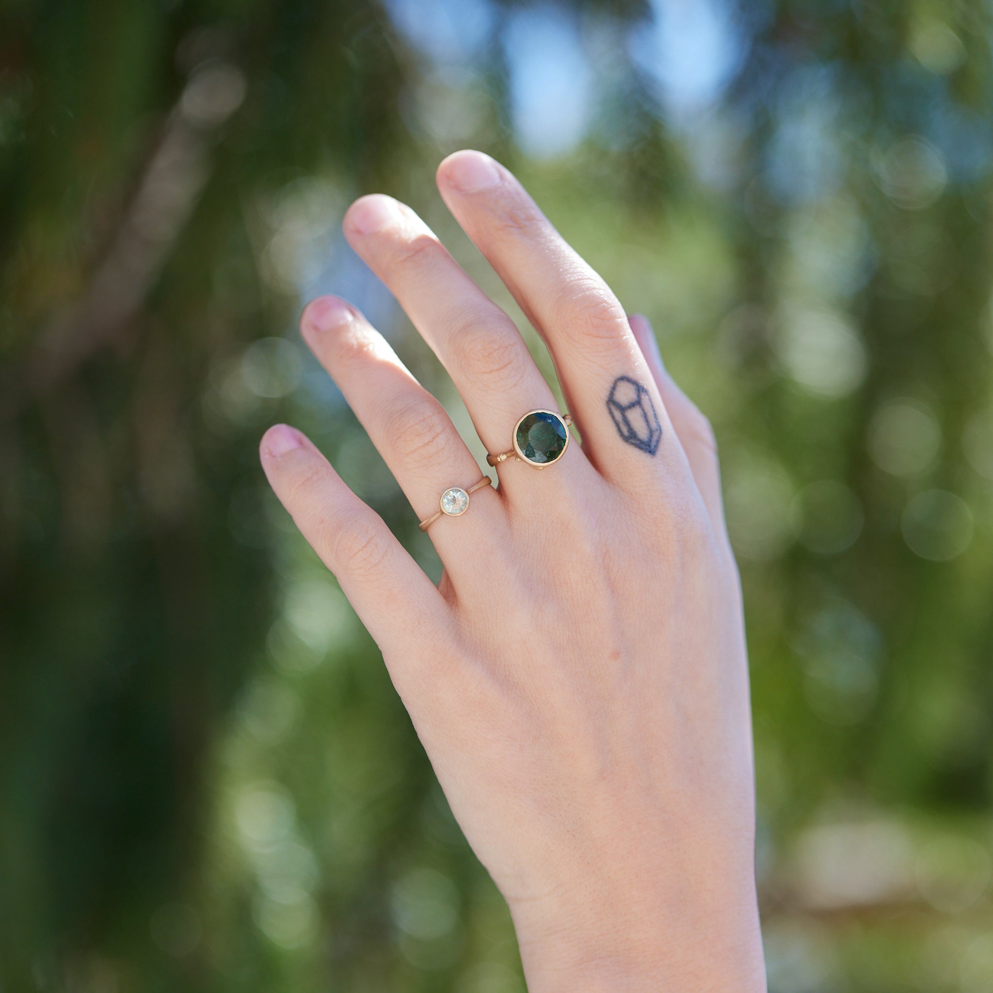 pale green round emerald set in gold bezel ring with silver barnacles. Photographed on person.