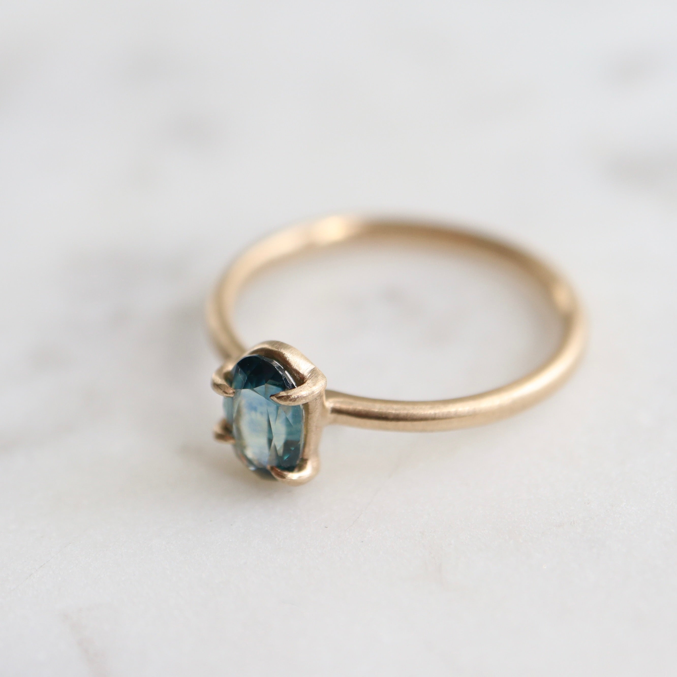 0.66ct Montana Sapphire Vanity Ring set in 14k gold with four prongs. The stone is an ocean blue. 