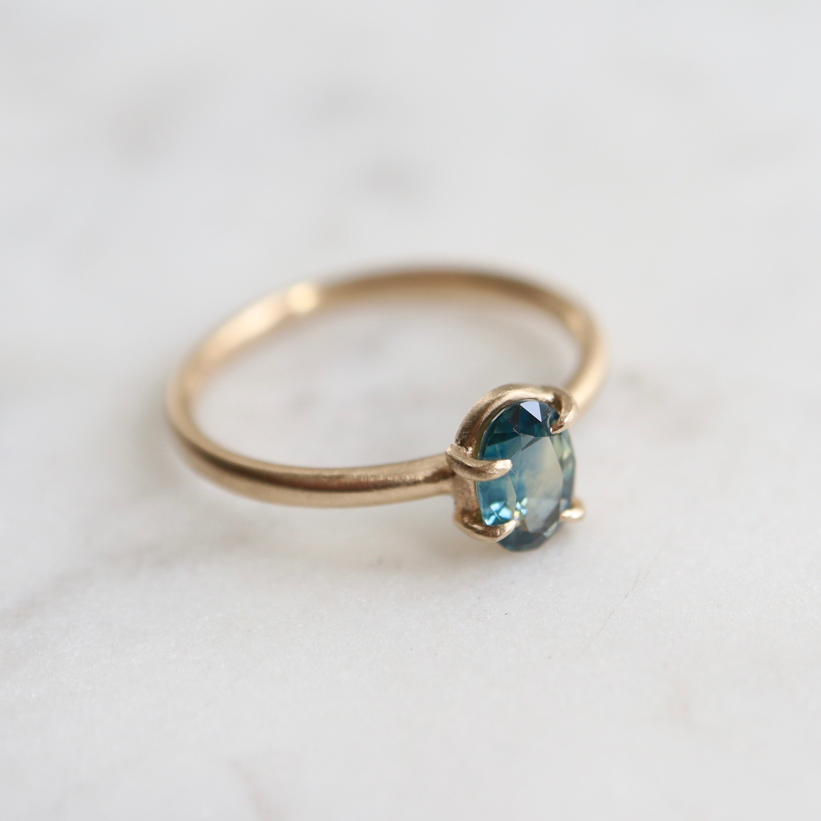 0.66ct Montana Sapphire Vanity Ring set in 14k gold with four prongs. The stone is an ocean blue. 