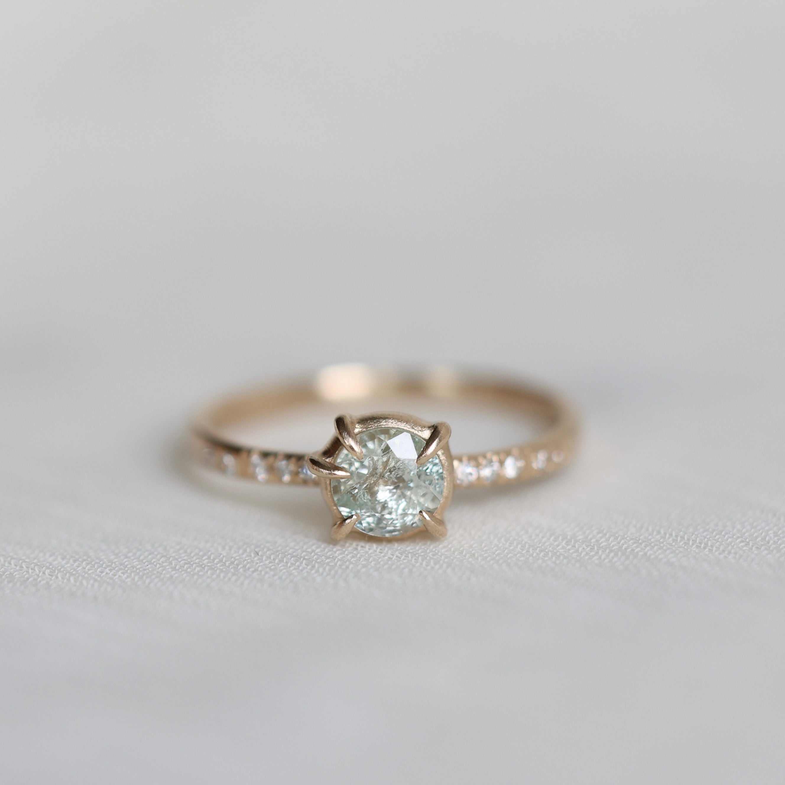 white sapphire center stone ring with diamond accents photographed against blurry grey background