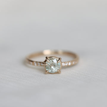 white sapphire center stone ring with diamond accents photographed against blurry grey background