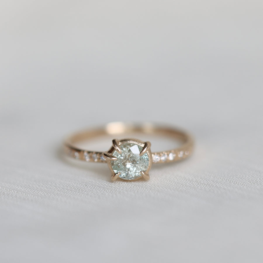 white sapphire center stone ring with diamond accents photographed against blurry grey background