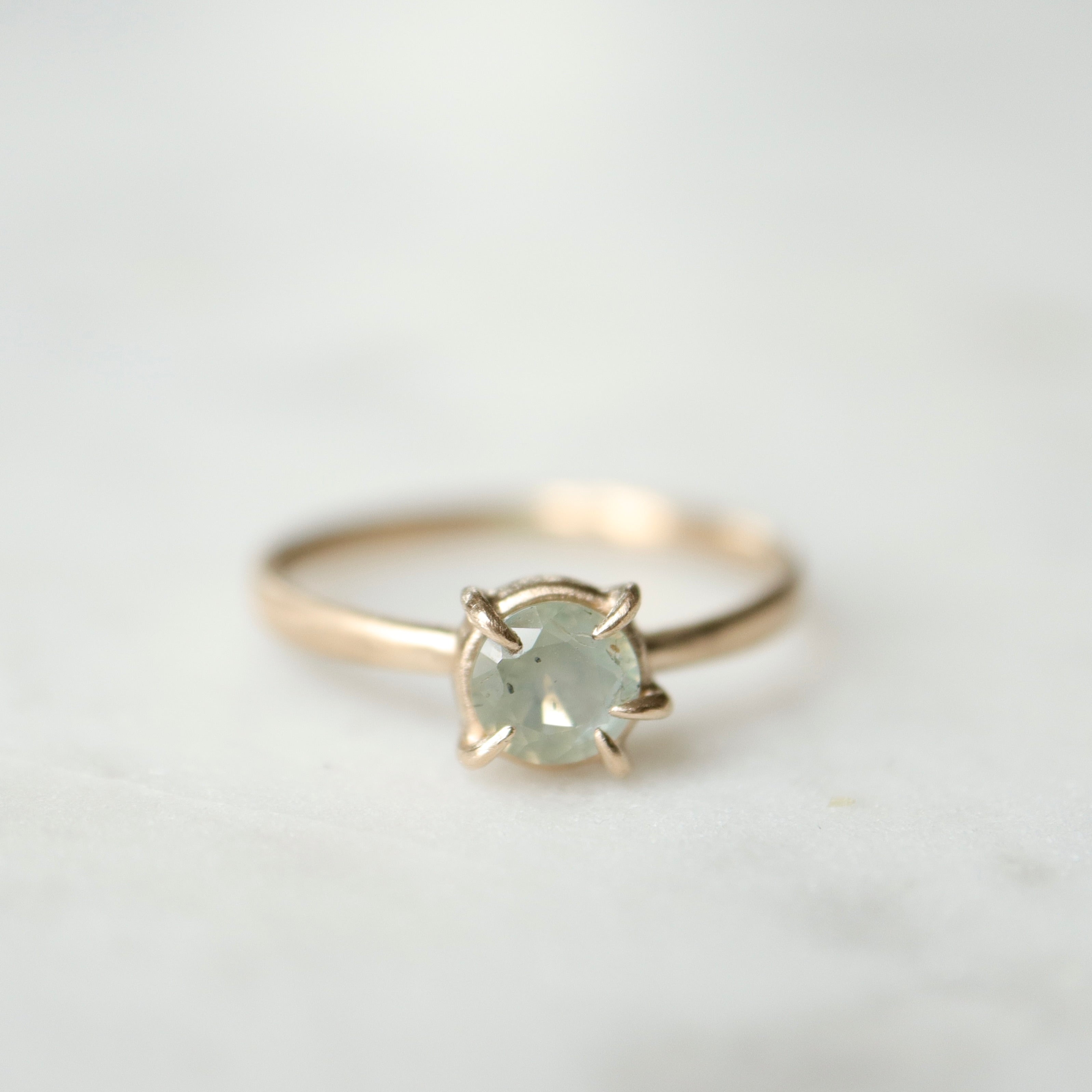 round cream montana sapphire set in a ring of prongs in a gold ring