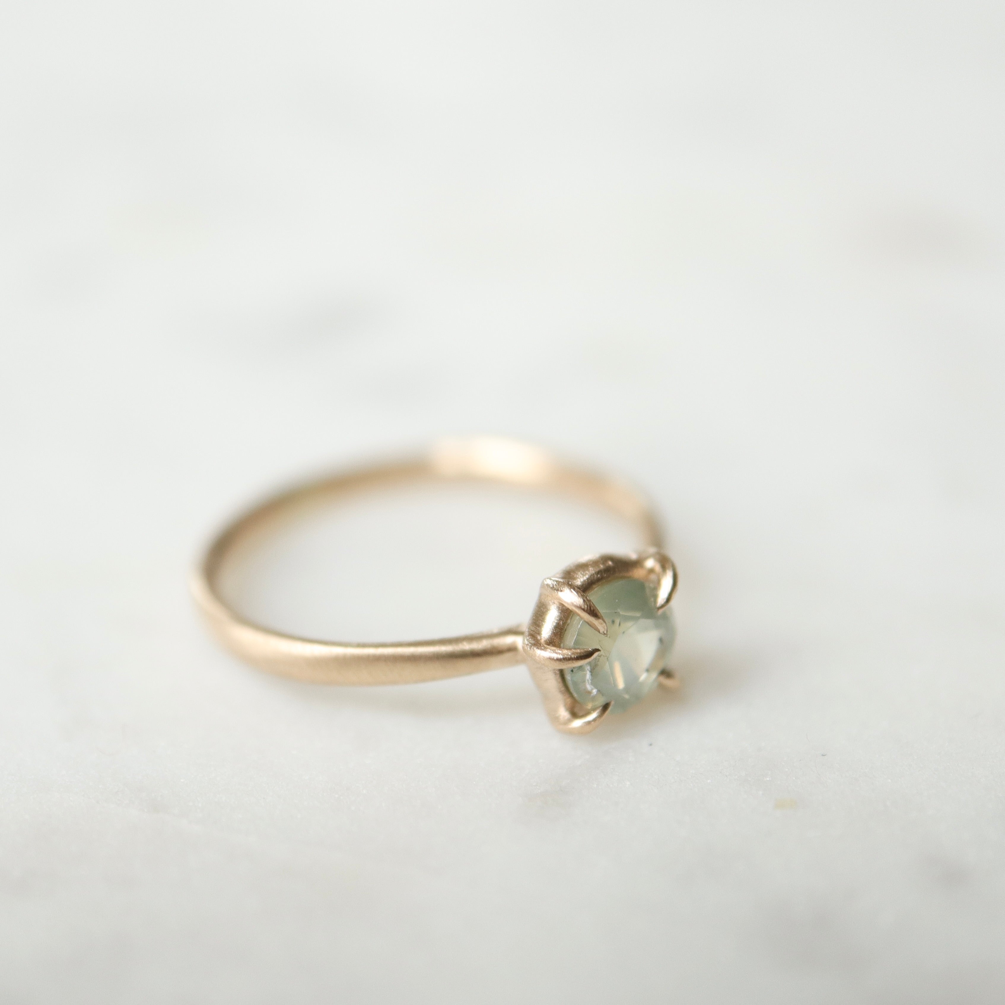 side view of round cream montana sapphire set in a ring of prongs in a gold ring