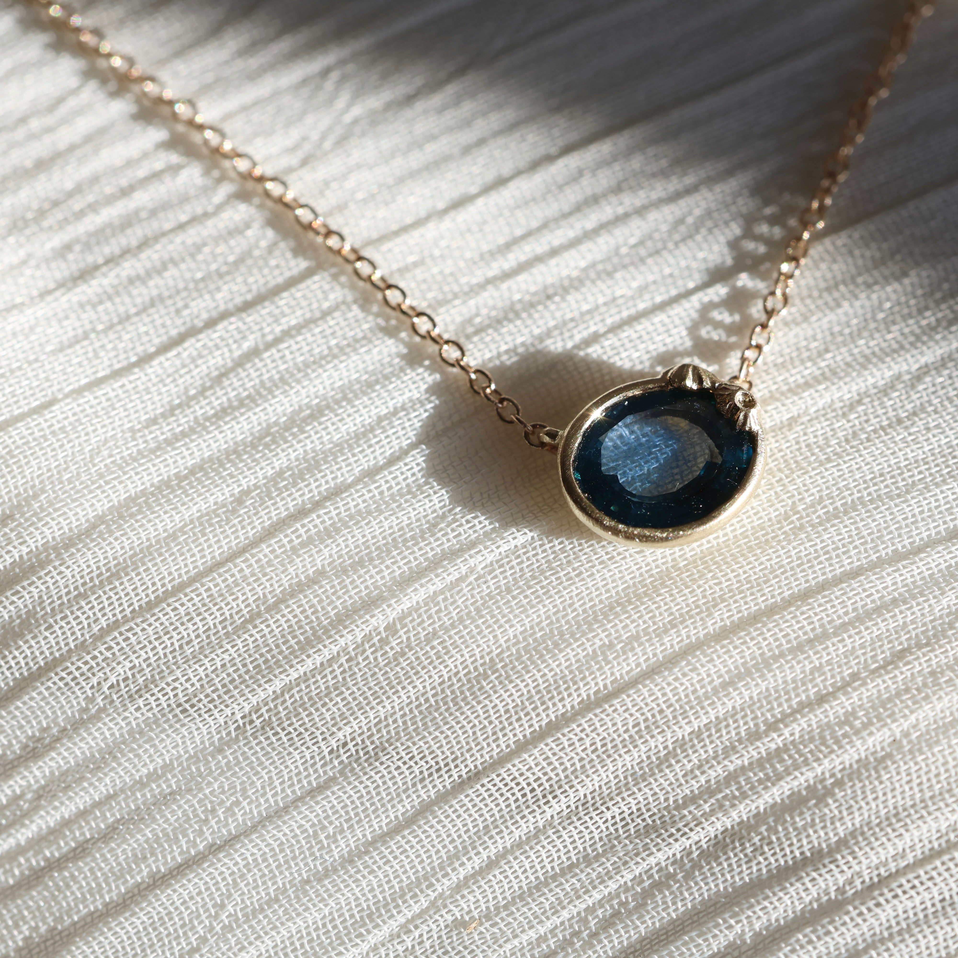 Necklace with a blue pendant on a white fabric background