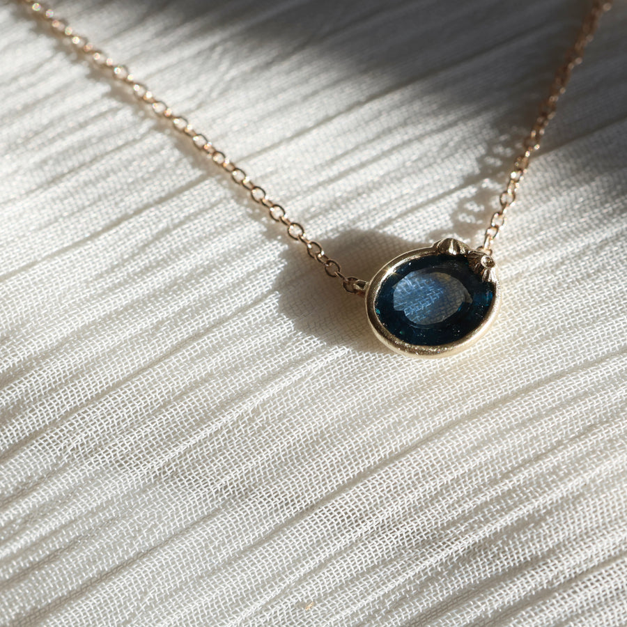 Necklace with a blue pendant on a white fabric background