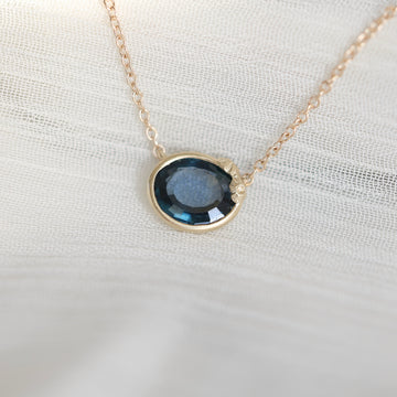 Necklace with a blue gemstone pendant on a white fabric background