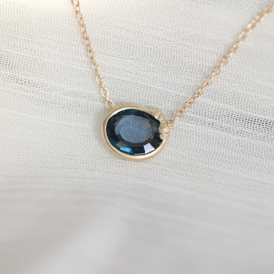 Necklace with a blue gemstone pendant on a white fabric background