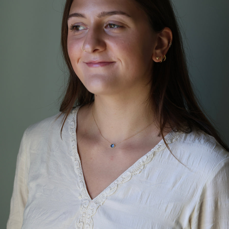 Woman wearing a white blouse with a necklace against a neutral background