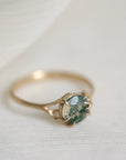 Gold ring with a green gemstone on a light fabric background