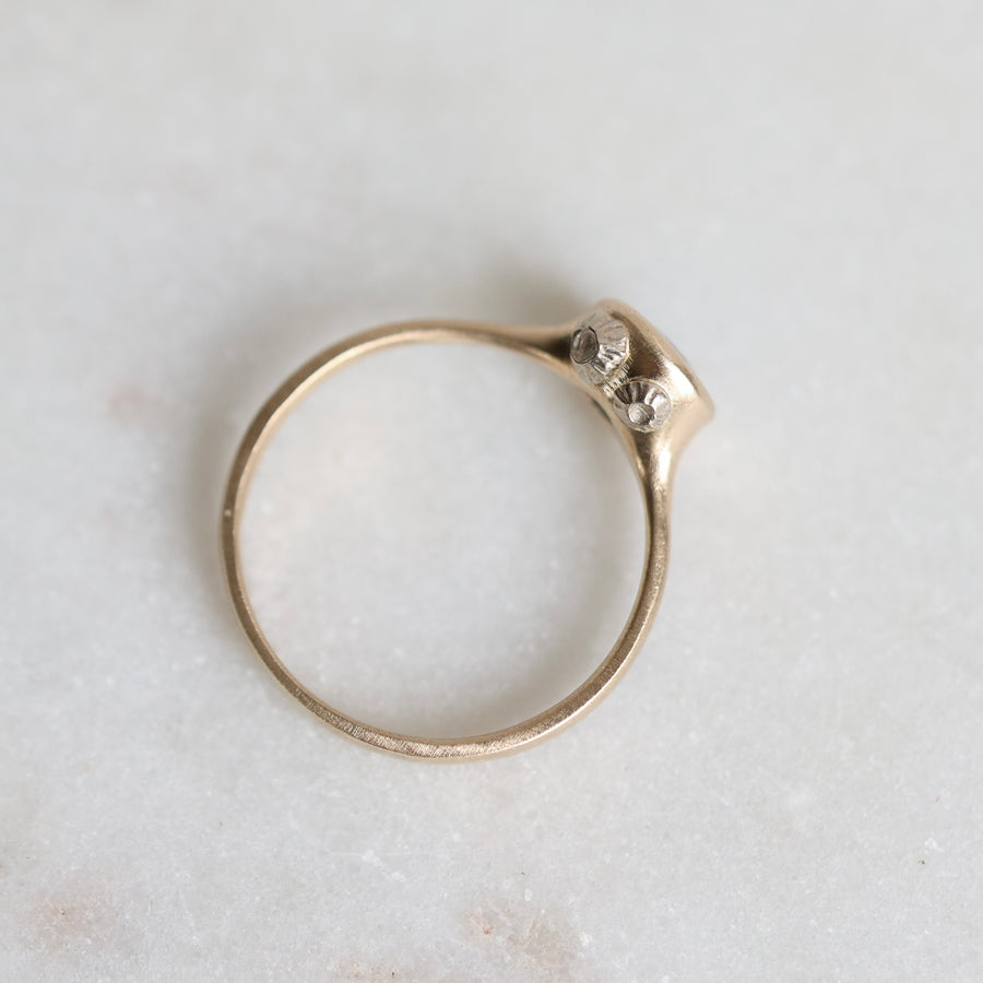 Gold ring with barnacles on a light marble background