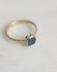 Gold ring with a blue gemstone on a light gray background