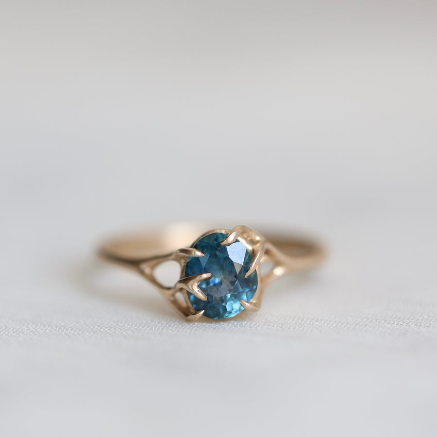 Gold ring with a blue gemstone on a light gray background