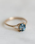 Gold ring with a blue gemstone on a white fabric background