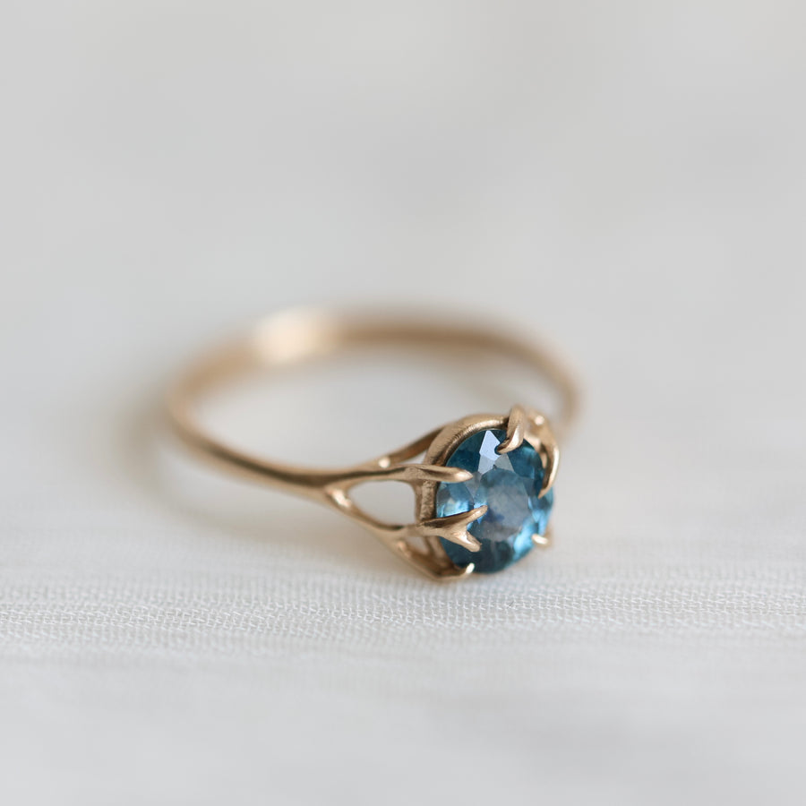 Gold ring with a blue gemstone on a white fabric background