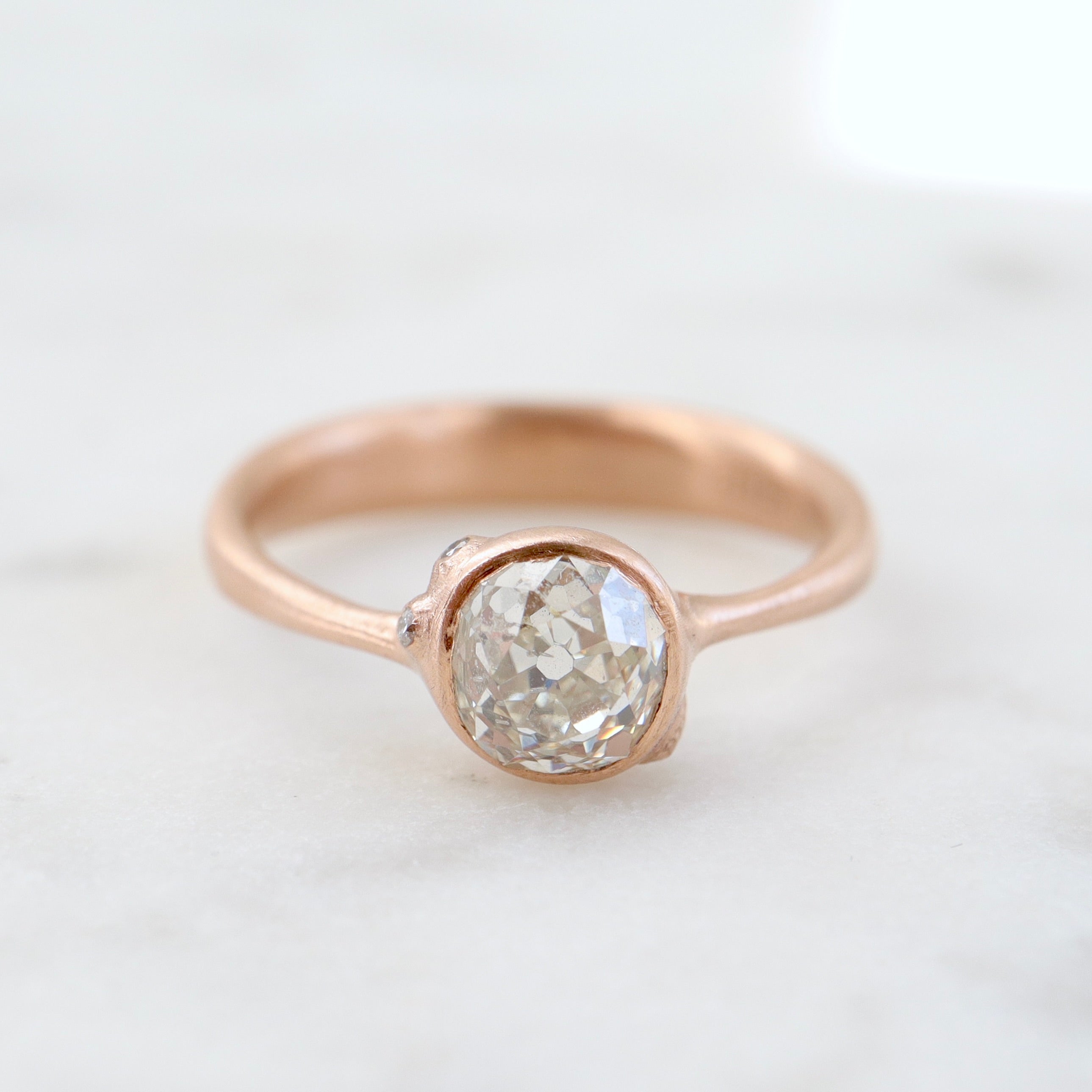 rose gold ring with diamond and three small side barnacles with diamonds- front view.