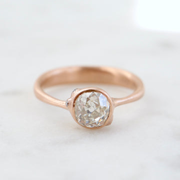 rose gold ring with diamond and three small side barnacles with diamonds- front view.