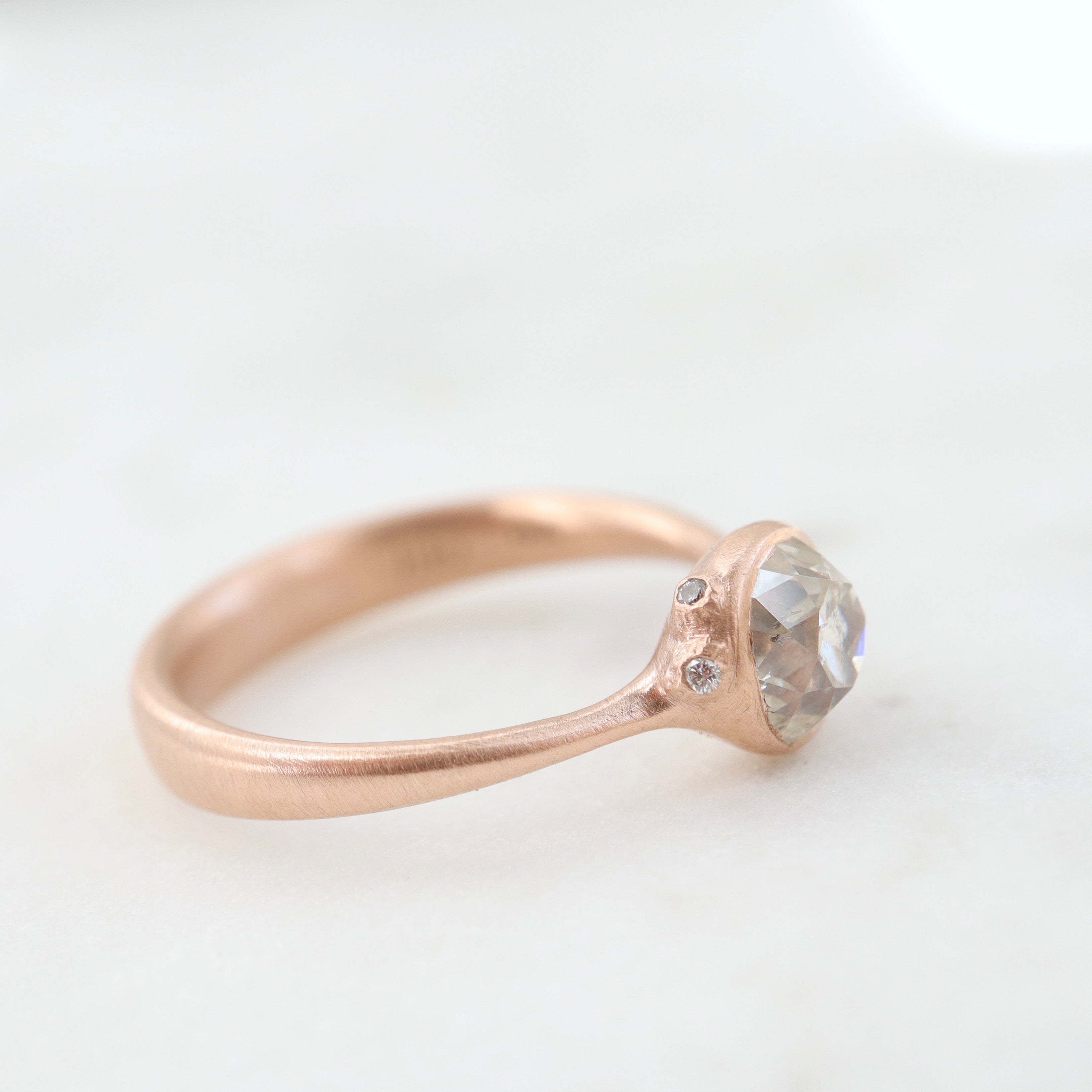 rose gold ring with diamond and three small side barnacles with diamonds- side view.