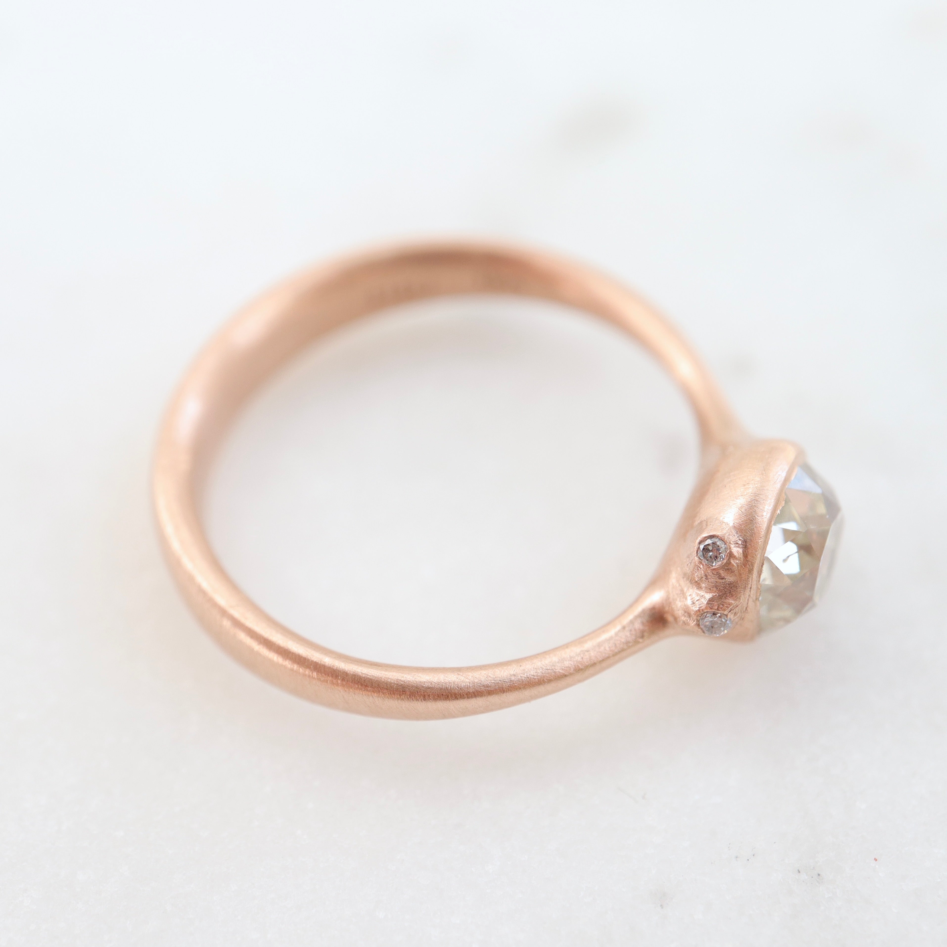 rose gold ring with diamond and three small side barnacles with diamonds- side view.
