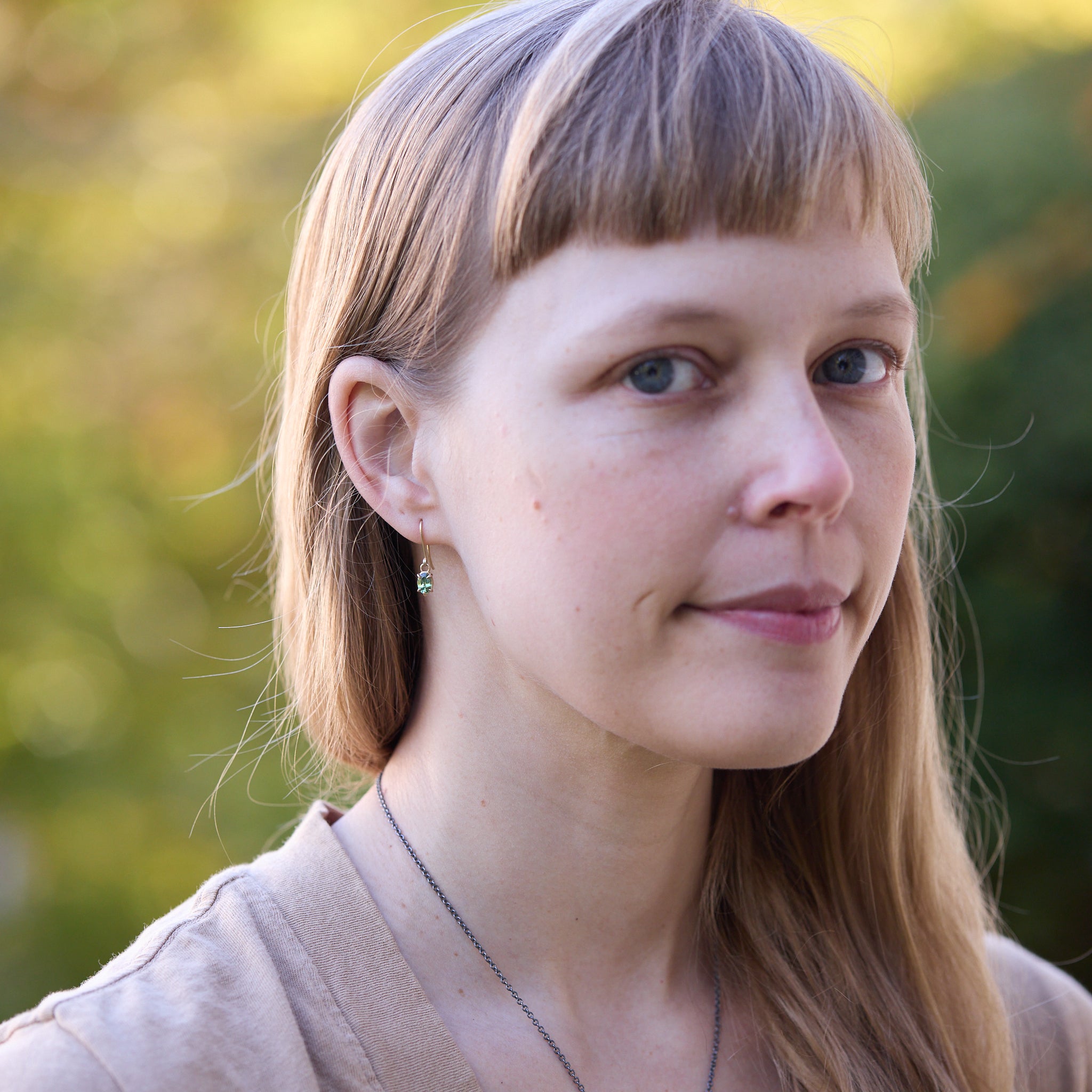 woman wearing tiny green earrings