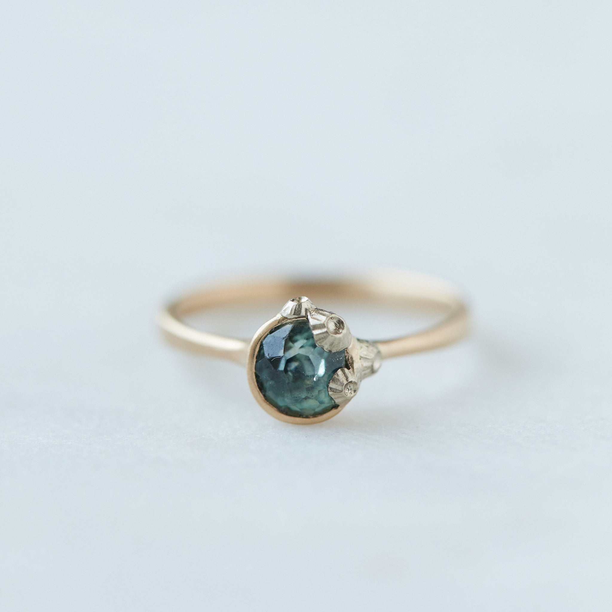 a half moon montana sapphire is set in a gold bezel ring with white gold barnacles. Front view.