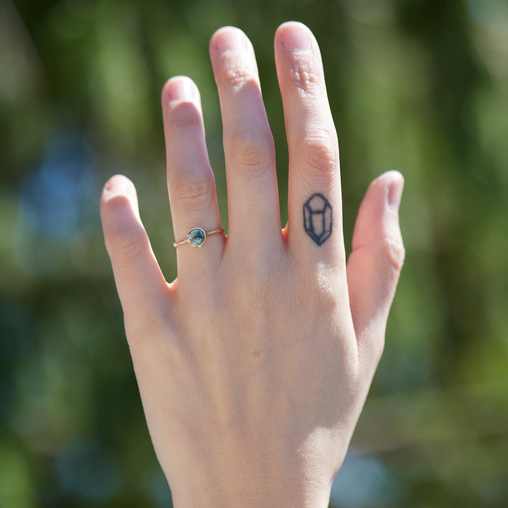 a half moon montana sapphire is set in a gold bezel ring with white gold barnacles. Photographed on hand.