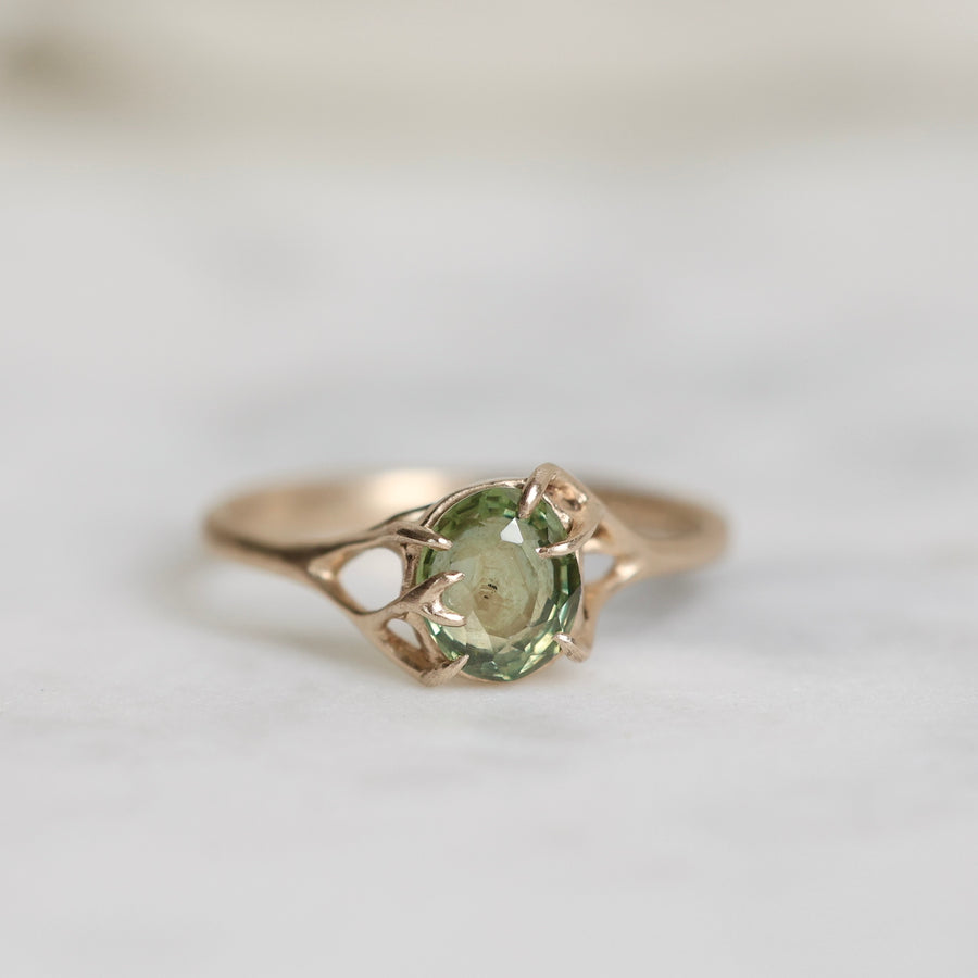 Gold ring with a green gemstone on a light background