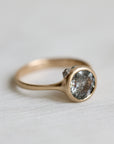 Gold ring with a textured gemstone on a light gray background