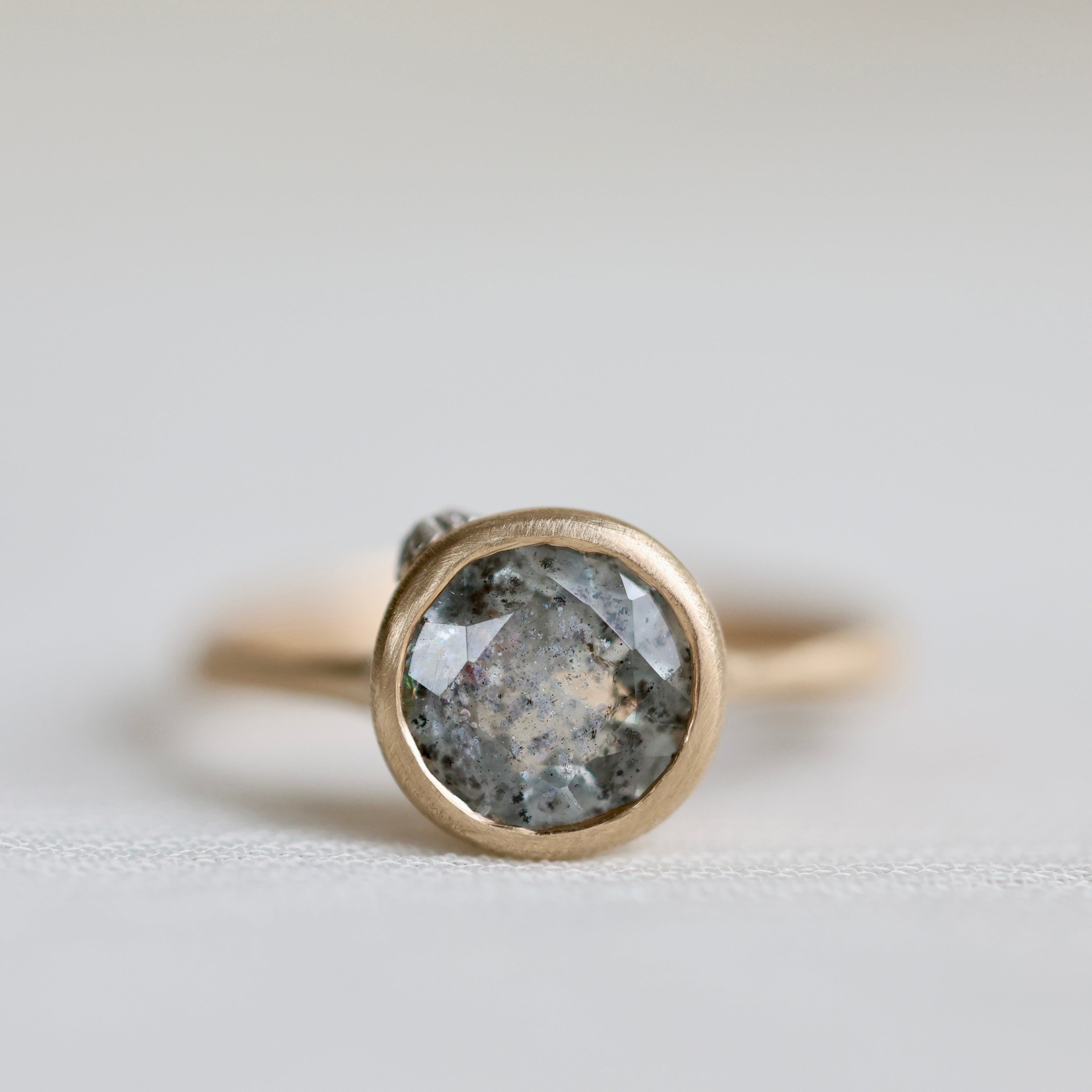 Gold ring with a large gemstone on a light gray background