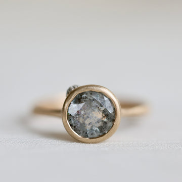 Gold ring with a large gemstone on a light gray background