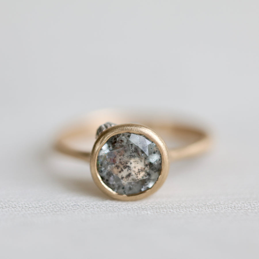 Gold ring with an aquamarine stone on a light gray background