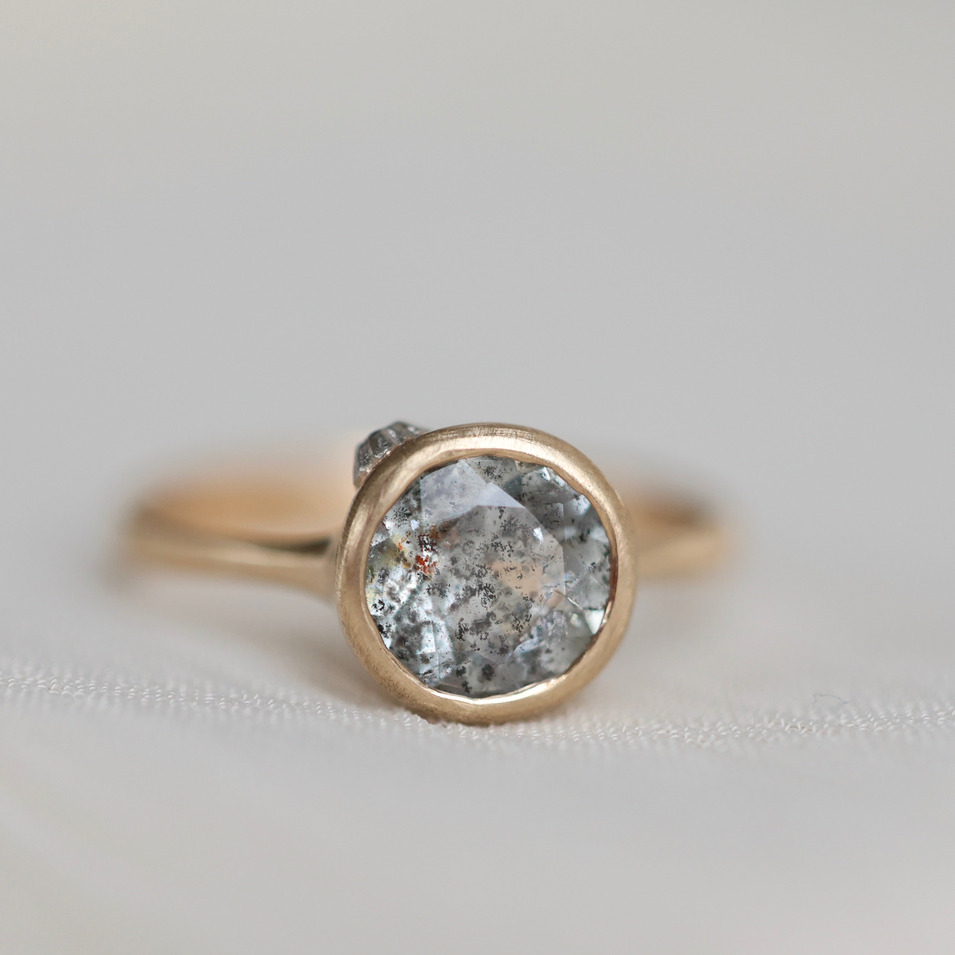 Gold ring with a gray stone on a light gray background