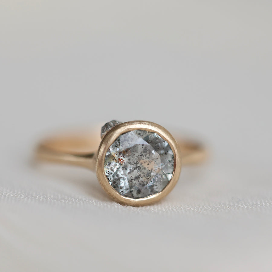 Gold ring with a gray stone on a light gray background