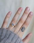 Hand wearing a ring with a small gemstone on a neutral background