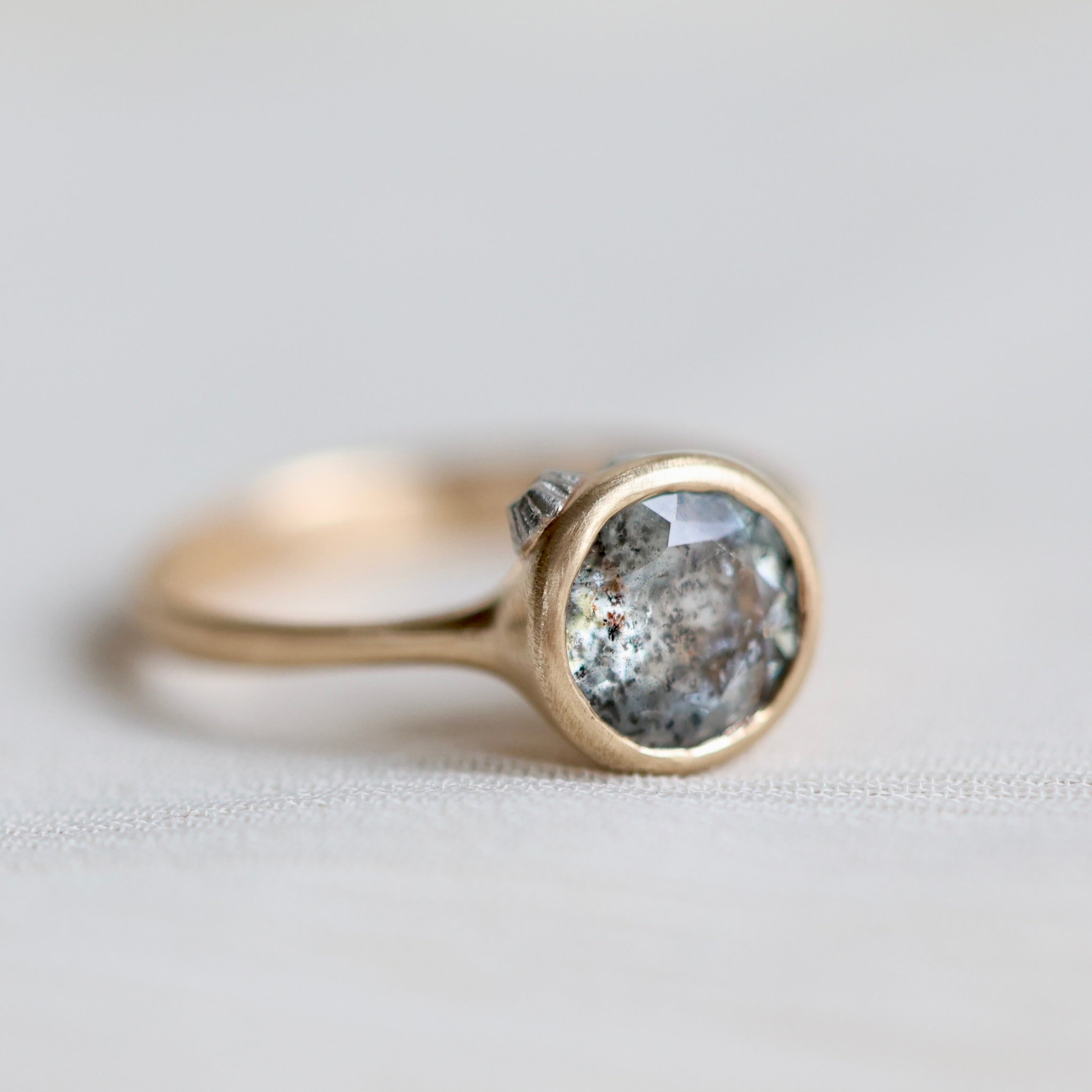 Gold ring with a gray stone on a light gray background